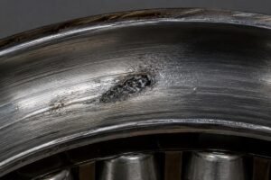 Contamination damage inside a spherical roller bearing raceway showing embedded particulate debris